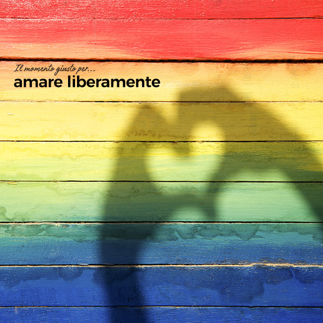 Muro colorato con colori di arcobaleno e ombra di mani che forma un cuore