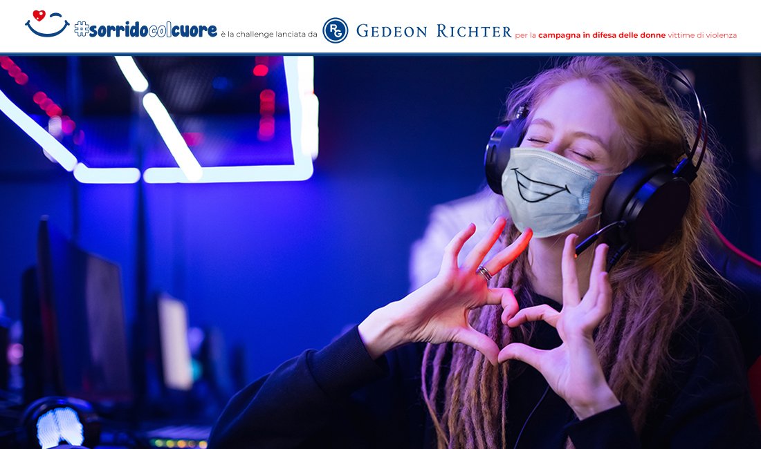 Una ragazza partecipa con mascherina, dita a forma di cuore e un sorriso alla video challenge SORRIDO COL CUORE di Gedeon Richter Italia