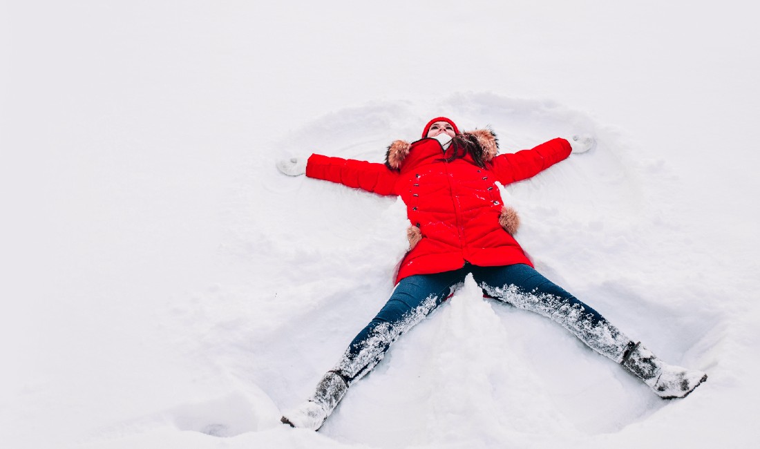 Prepararsi ad affrontare l'inverno: nell'immagine una ragazza crea un angelo di neve.