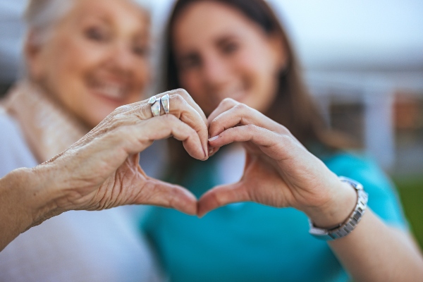 Concept ''come costruire una relazione sana'': nonna e nipote formano un cuore con le mani unite