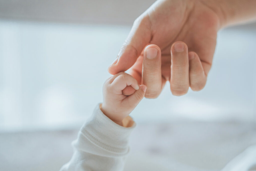 Concept per rapporto tra genitori e figli: mano di neonato e genitore che si stringono