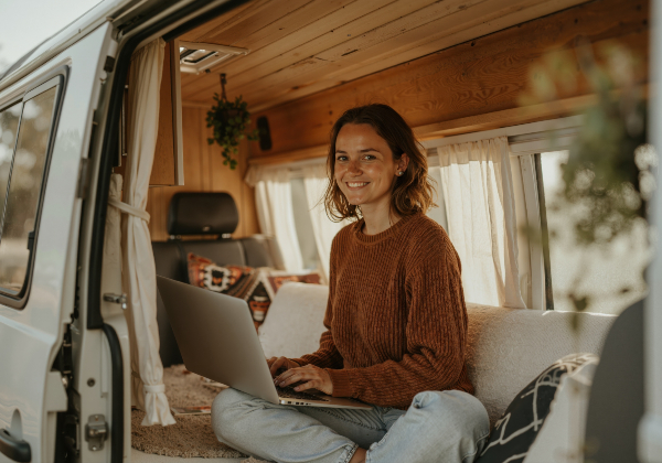 Concept per nomadi digitali: ragazza lavora con computer portatile in un camper
