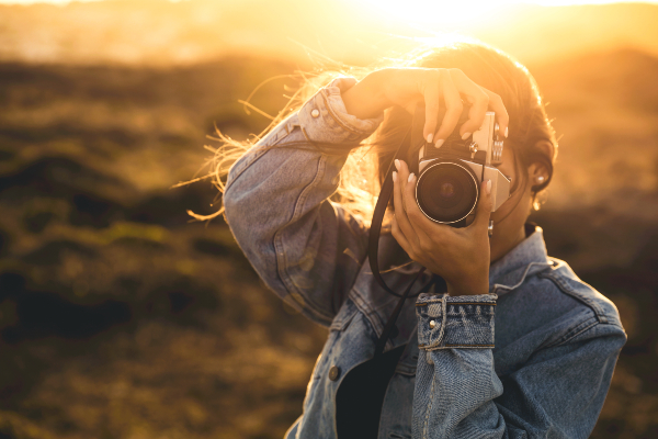 Concept per attività da fare nel tempo libero: primo piano di donna mentre scatta una foto con la macchina fotografica